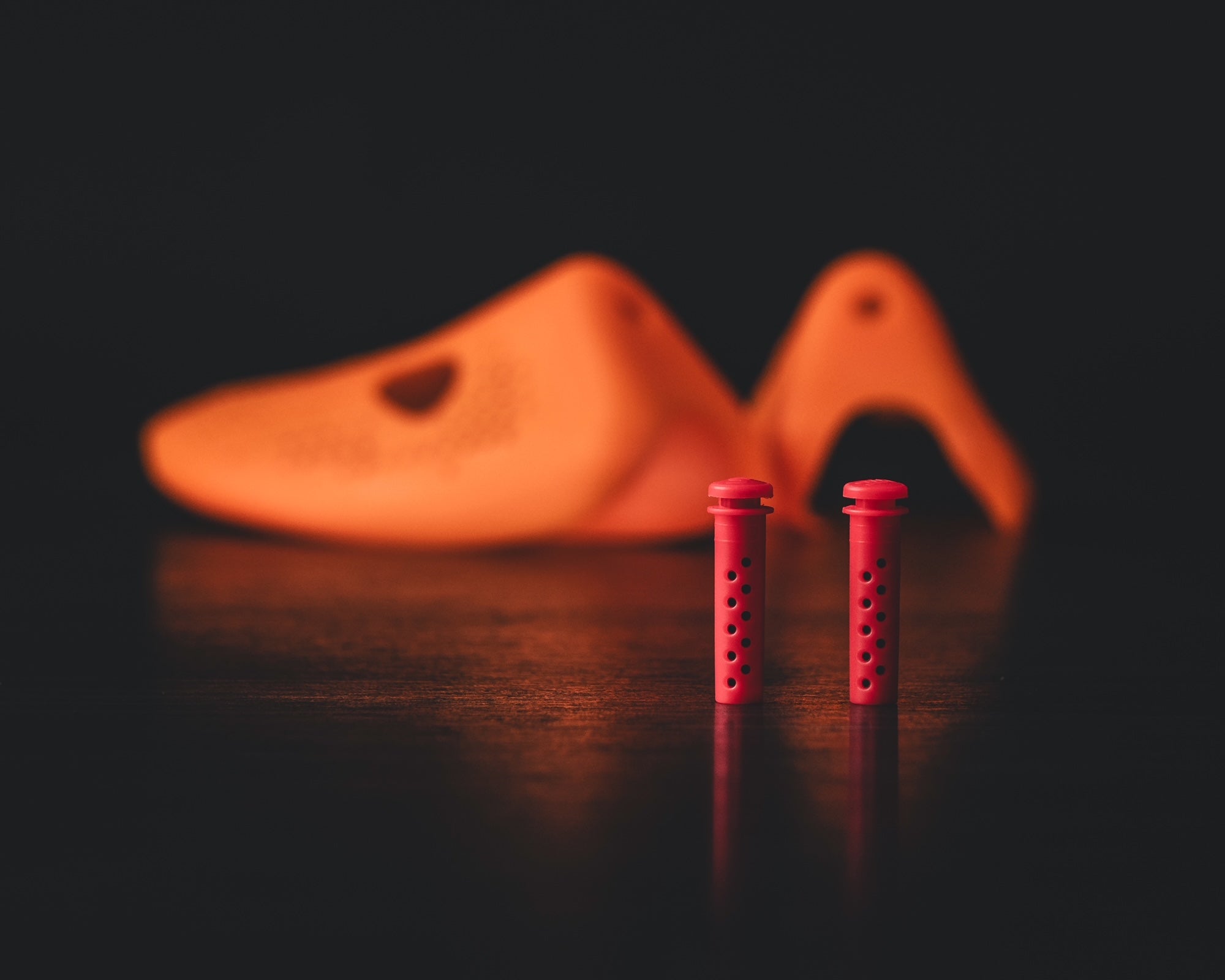 Stinky Sneakers shoe insert in red with orange shoe background designed for eliminating odors.